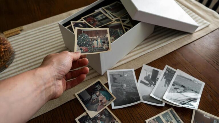 Dłoń trzymająca stare fotografie rodzinne – symbol tego, co zostawiamy po sobie, pamięci o przodkach i bliskich oraz tego, jak pielęgnować pamięć o nich.