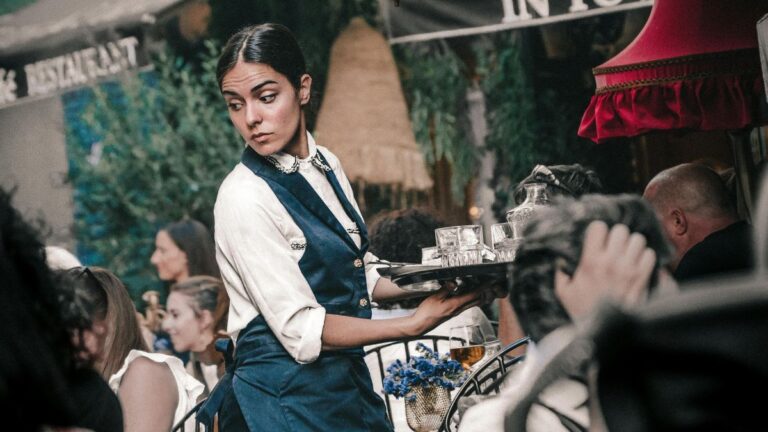 Praca w usługach: czarnowłosa kelnerka obsługuje klientów. Fot. Fot. Peter Chirkov / Pexels