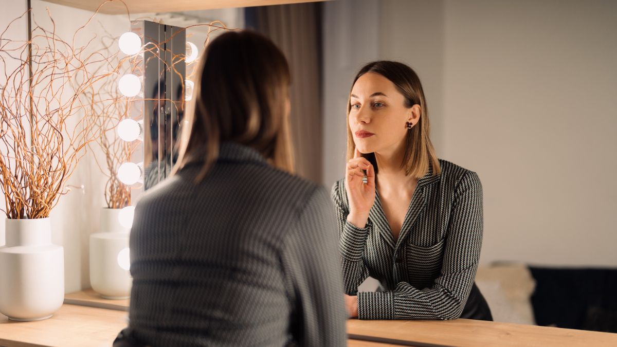 Wygląd w pracy: pewna siebie, elegancko ubrana kobieta, przegląda się w lustrze. Fot ArthurHidden / freepik