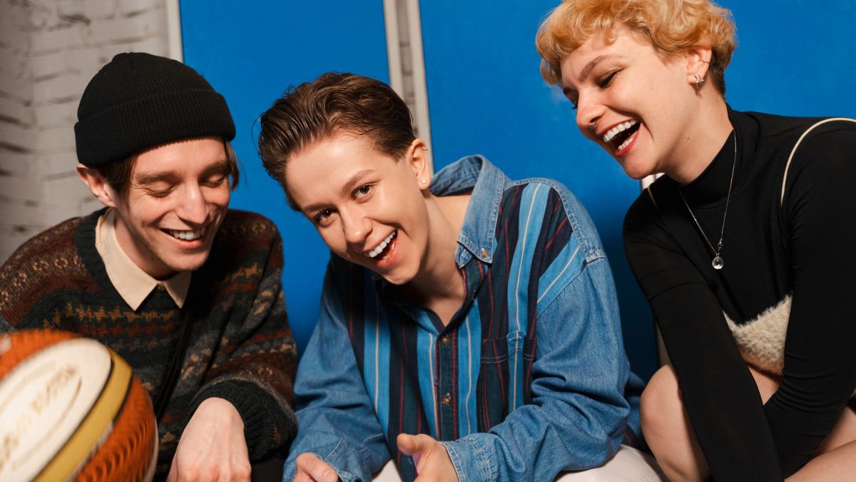 Młodzieżowe Słowo Roku 2025: grupa nastolatków siedzi, śmieje się i rozmawia, jedna z nich trzyma smartfon. Fot. Freepik.