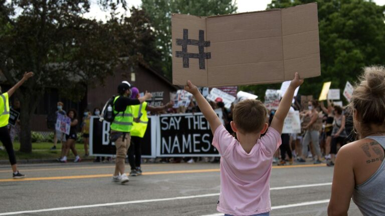 Partie w USA: mały chłopiec trzyma kartonowy transparent podczas protestu. Fot. Forest S / Unsplash
