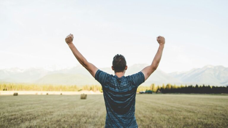 mężczyzna unosi ręce w geście zwycięstwa na tle natury, symbol wygranej z uzależnieniem i nowej nadziei dzięki odkryciom o Ozempicu