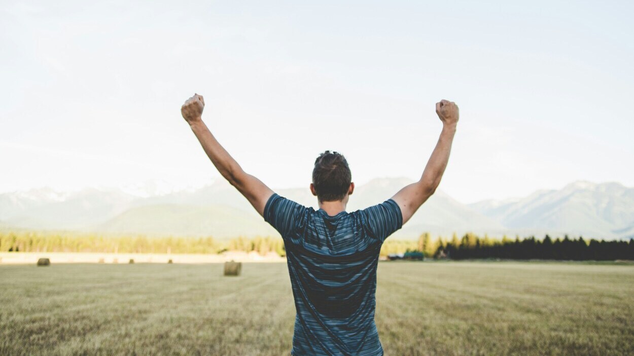 mężczyzna unosi ręce w geście zwycięstwa na tle natury, symbol wygranej z uzależnieniem i nowej nadziei dzięki odkryciom o Ozempicu