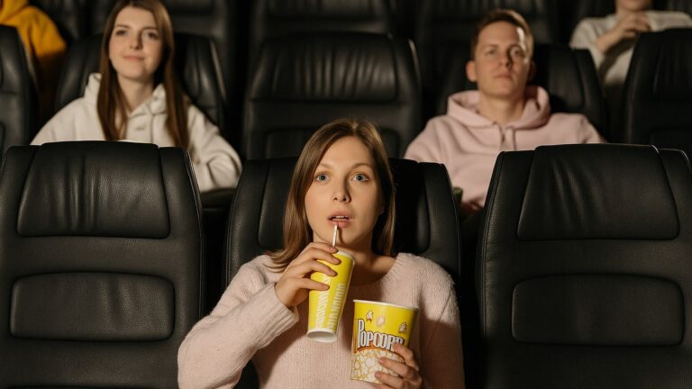 Kobieta ogląda film w kinie, skupiona i poruszona sceną na ekranie – przykład wpływu filmów na emocje człowieka.