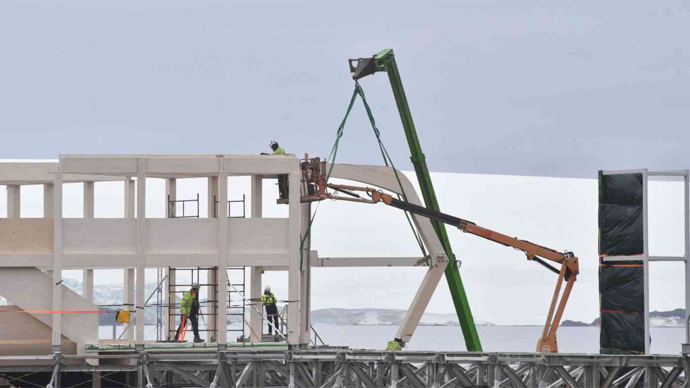 konstrukcja budynku wokół niego robotnicy i śnieg