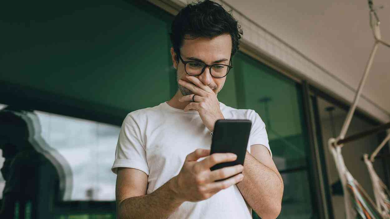 Młody mężczyzna patrzący w telefon podczas detoksu od mediów społecznościowych