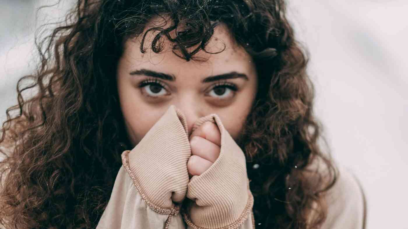 Brunetka trzyma dłonie przy twarzy