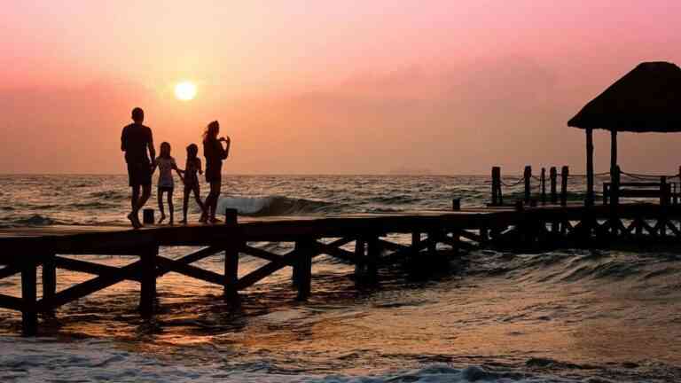 Demografia w kryzysie. Na zdjeciu rodzina stojąca na pomoście na tle zachodzącego słońca.