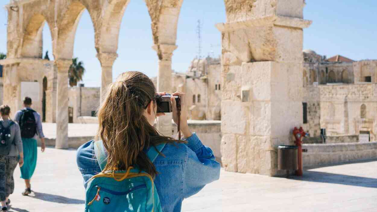 Młoda turystka z plecakiem robi zdjęcie zabytkowej architektury podczas miejskiego wyjazdu