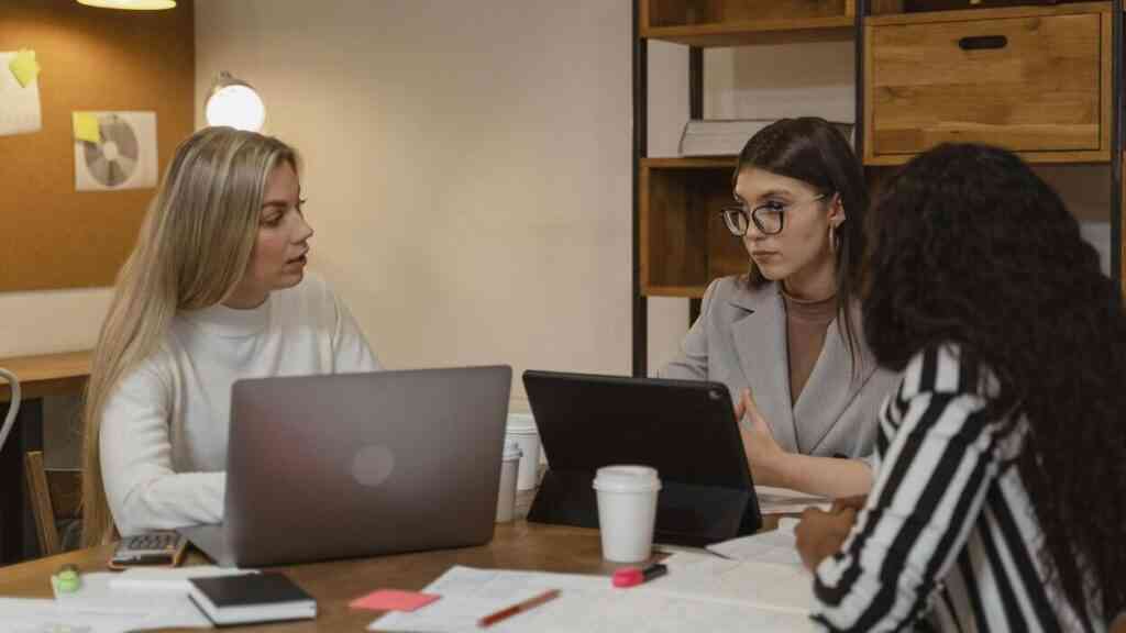 Spotkanie młodych pracowników przy laptopach – zmiany na rynku pracy widoczne w codziennej pracy zespołowej