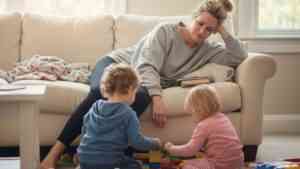 matka smutna siedzi na kanapie, obok bawią się dzieci