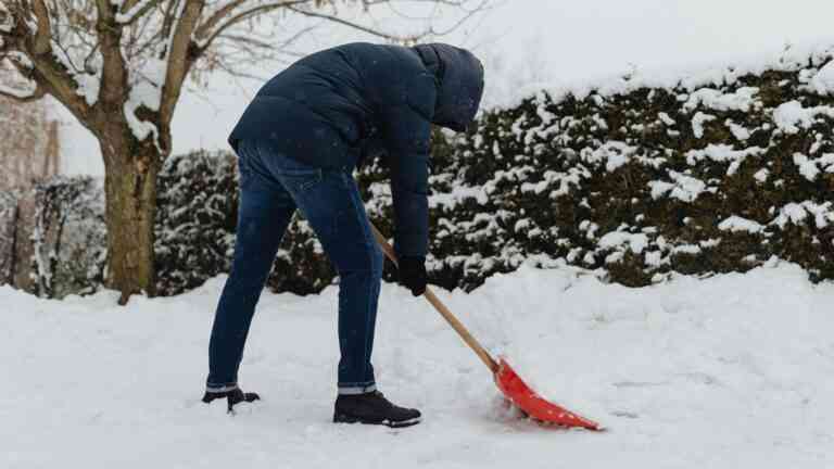 Mężczyzna zgarniający łopatą śnieg