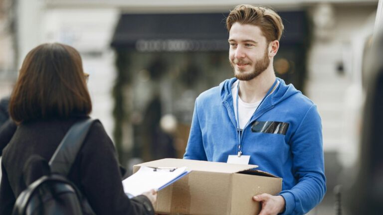 mężczyzna w niebieskiej bluzie przekazuje paczkę kobiecie