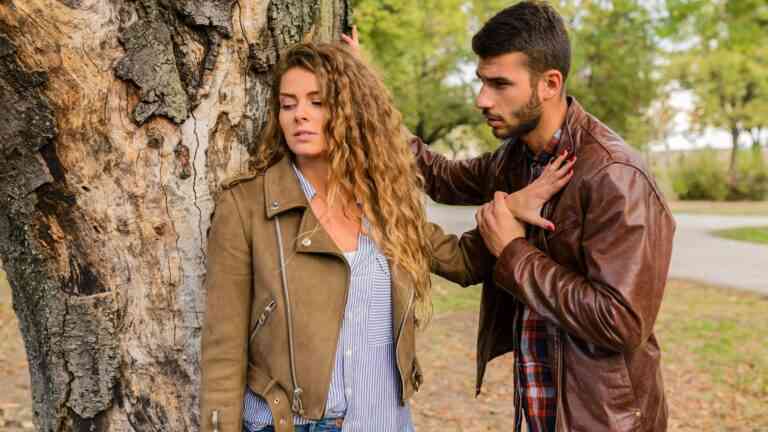 kobieta odtrąca mężczyznę przy drzewie