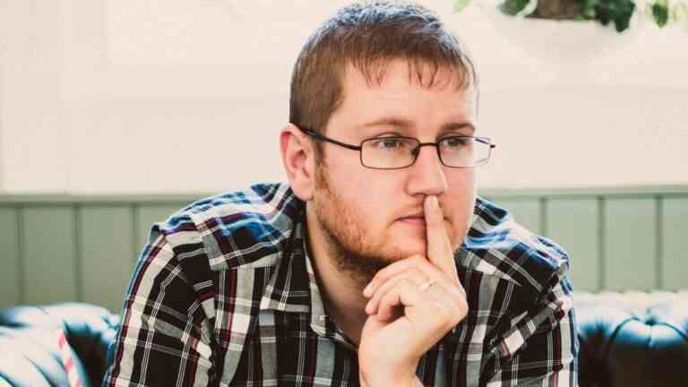 Mężczyzna w okularach siedzi zamyślony, podpierając twarz dłonią – ilustracja tematu kłopotów z pamięcią i koncentracją.