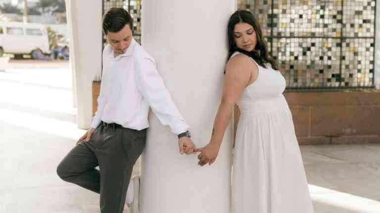 Miłość po latach. Kobieta i mężczyzna trzymają się za palce, opierając się o słup