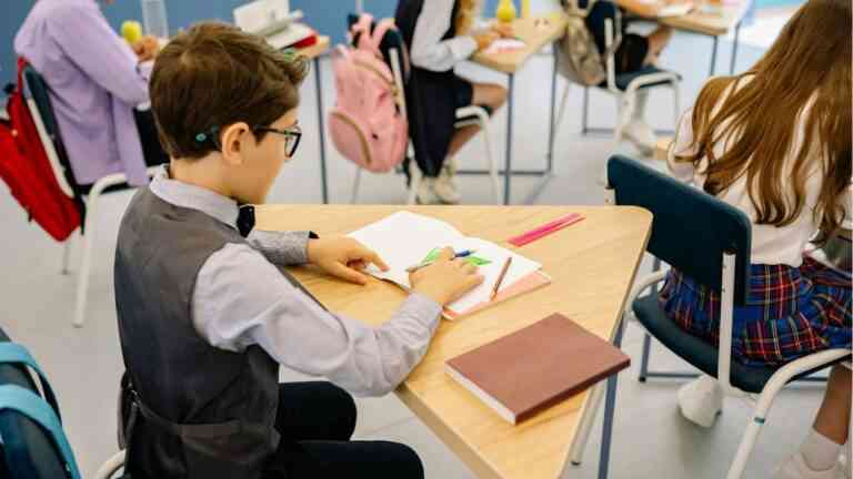 dzieci siedzą w ławkach w szkole