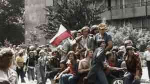 Tłum ludzi siedzących na ciężarówce podczas protestu w PRL; młodzi robotnicy i mieszkańcy trzymają biało-czerwoną flagę w czerwcu 1976 roku w Radomiu.