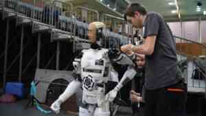 Mężczyzna składający robota humanoidalnego w Chinach.