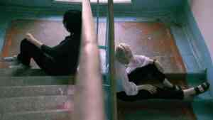 Dwie osoby siedzą na schodach tyłem do siebie. Zdjęcie ilustruje wpływ miejsca zamieszkania i konfliktów sąsiedzkich na długość życia.