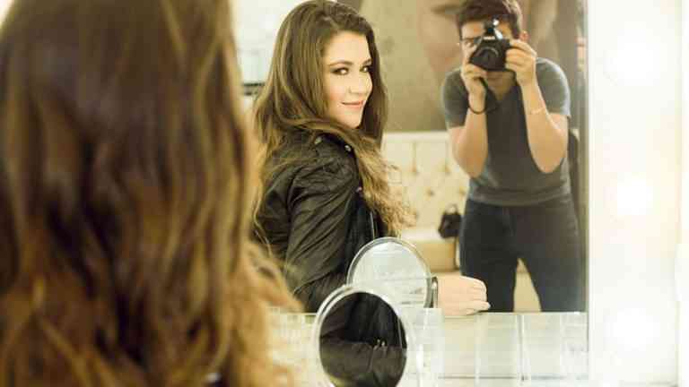 kobieta przegląda się w lustrze, mężczyzna robi jej zdjęcie