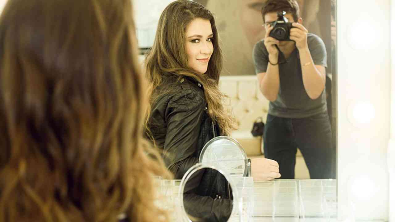 kobieta przegląda się w lustrze, mężczyzna robi jej zdjęcie