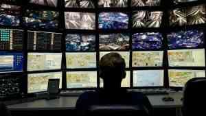 Człowiek siedzący przed ścianą ekranów z wieloma obrazami i danymi – symbol świata nadmiaru informacji i potrzeby samodzielnego myślenia społecznego