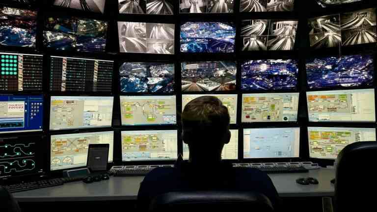 Człowiek siedzący przed ścianą ekranów z wieloma obrazami i danymi – symbol świata nadmiaru informacji i potrzeby samodzielnego myślenia społecznego