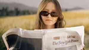 kobieta czyta gazetę w okularach za nią łąka