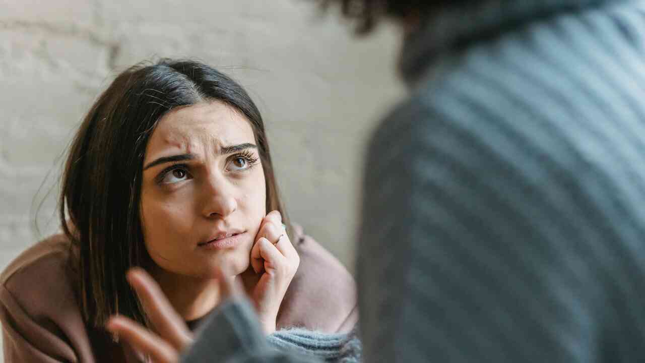 Kobieta słucha w napięciu podczas trudnej rozmowy, emocje po zranieniu w relacji