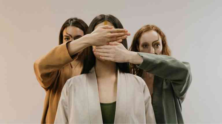 trzy kobiety, dwie z nich zasłaniają twarz trzeciej