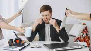 Mężczyzna przy biurku przytłoczony obowiązkami – emocje w pracy i stres zawodowy