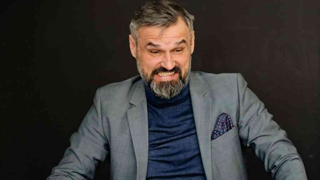 Mężczyzna reaguje emocjonalnie przy biurku – inteligencja emocjonalna praca i emocje a decyzje