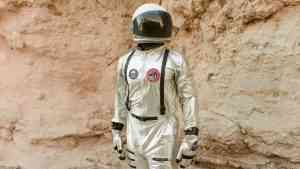 kosmonauta w skafandrze stoi i pozuje na tle skały, bedąc wzorcem jak spełniać marzenia
