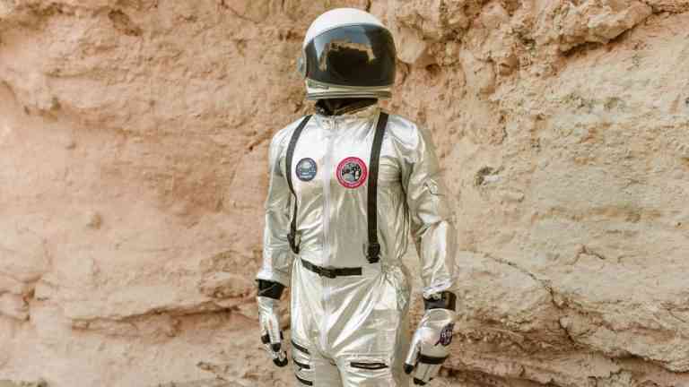kosmonauta w skafandrze stoi i pozuje na tle skały, bedąc wzorcem jak spełniać marzenia