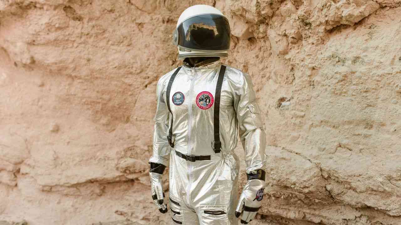 kosmonauta w skafandrze stoi i pozuje na tle skały, bedąc wzorcem jak spełniać marzenia