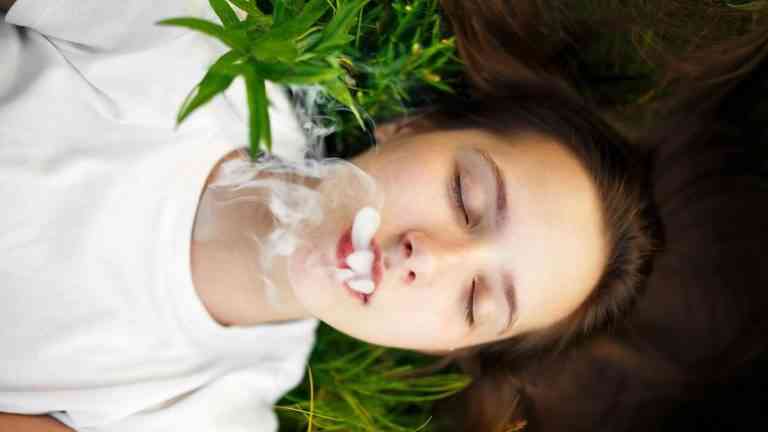 młoda dziewczyna zaciąga się dymem, nie wie, że marihuana szkodzi mózgowi nastolatka