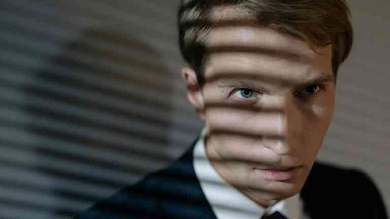 twarz mężczyzny w garniturze , który rzuca cień wskazując na relację: osobowość a wybór kariery