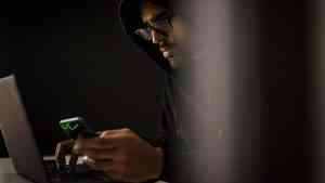 Mężczyzna w kapturze siedzący przy komputerze obrazuje relację: kryzys męskości i manosfera w sieci