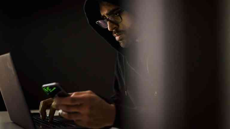 Mężczyzna w kapturze siedzący przy komputerze obrazuje relację: kryzys męskości i manosfera w sieci