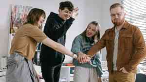 grupa młodych ludzi stoi wokół siebie i styka się dłońmi.