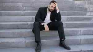 mężczyzna siedzi na schodach i wygląda na zniechęconego, poczucie stagnacji i braku postępu w życiu