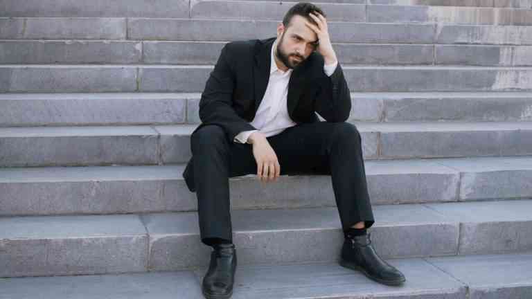 mężczyzna siedzi na schodach i wygląda na zniechęconego, poczucie stagnacji i braku postępu w życiu
