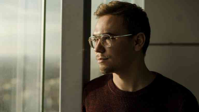 Półzbliżenie na twarz młodego mężczyzny w okularach który patrzy na okno