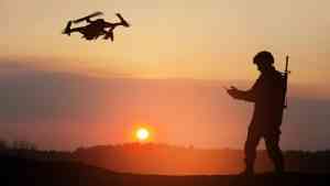 Sylwetka żołnierza sterującego dronem o zachodzie słońca jako symbol tego, czym jest wojna hybrydowa i wojna bez wypowiedzenia