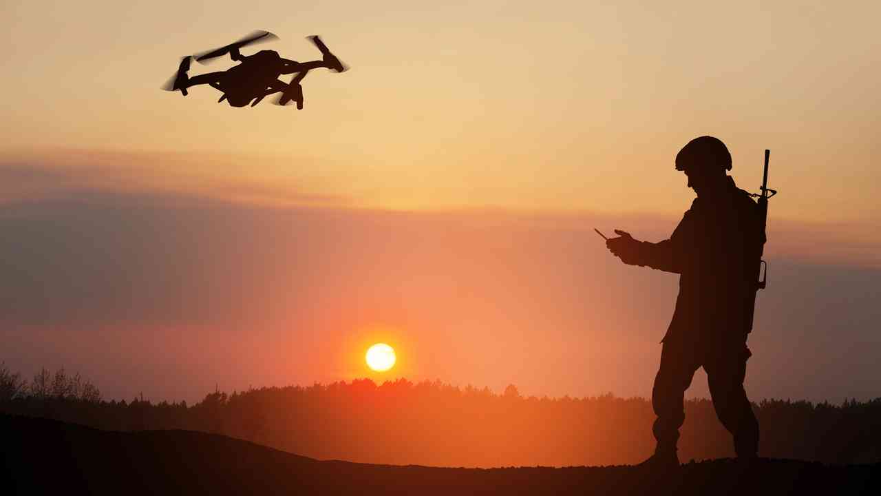 Sylwetka żołnierza sterującego dronem o zachodzie słońca jako symbol tego, czym jest wojna hybrydowa i wojna bez wypowiedzenia