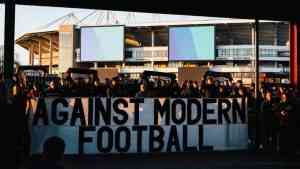 Kibice z transparentem "Against Modern Football" – obraz komercjalizacji piłki nożnej, która budzi bunt.