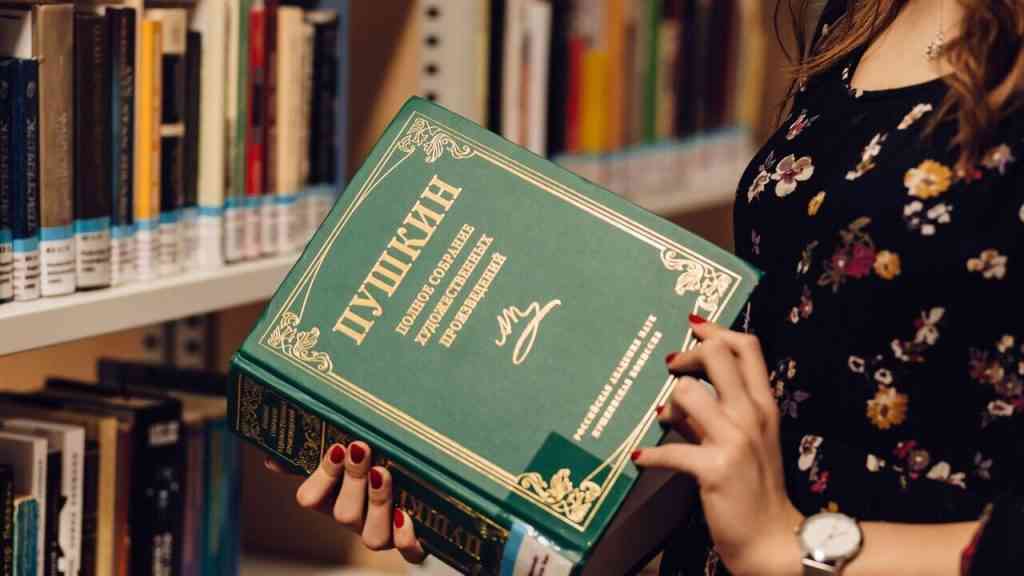Kobieta trzyma tom rosyjskiej literatury w bibliotece. Zdjęcie ilustruje felieton Jacka Piekary o książkach czytanych w PRL mimo niechęci do sowieckiej Rosji.