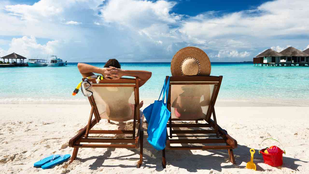 Para odpoczywa na leżakach przy turkusowym morzu podczas wakacji all inclusive