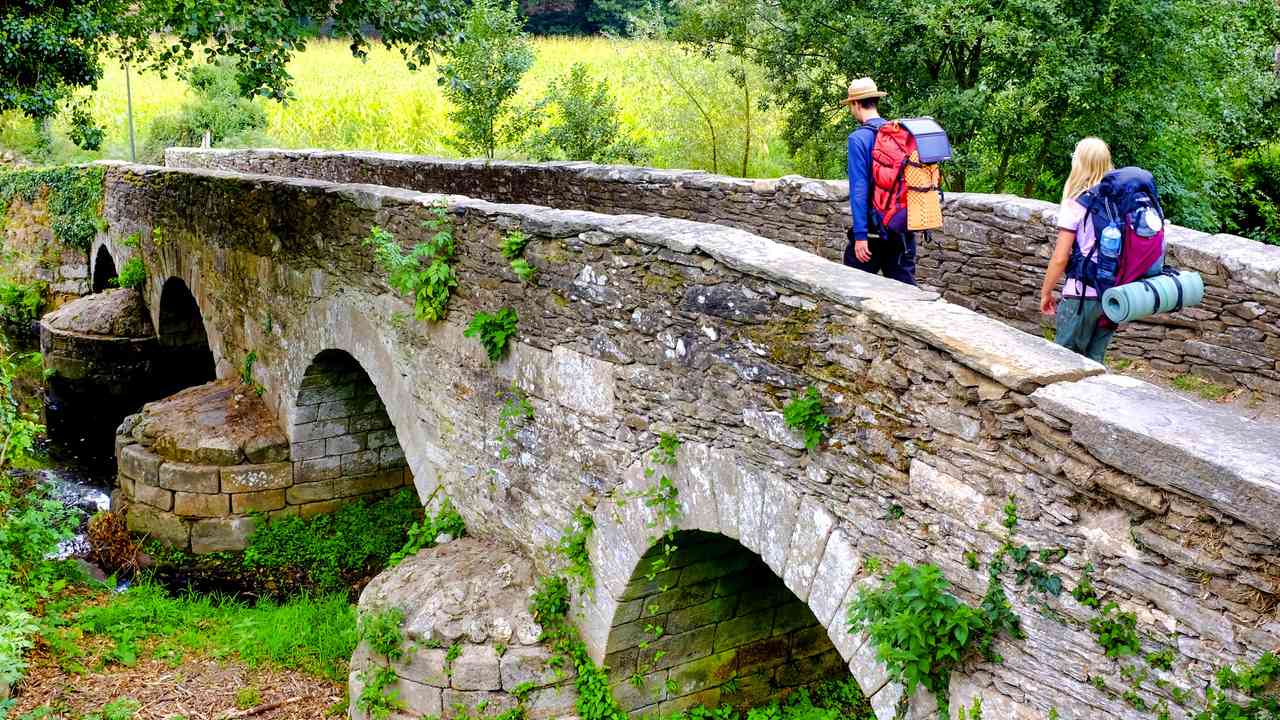 Pielgrzymi na Ponte da Áspera podczas wędrówki Camino de Santiago w Hiszpanii